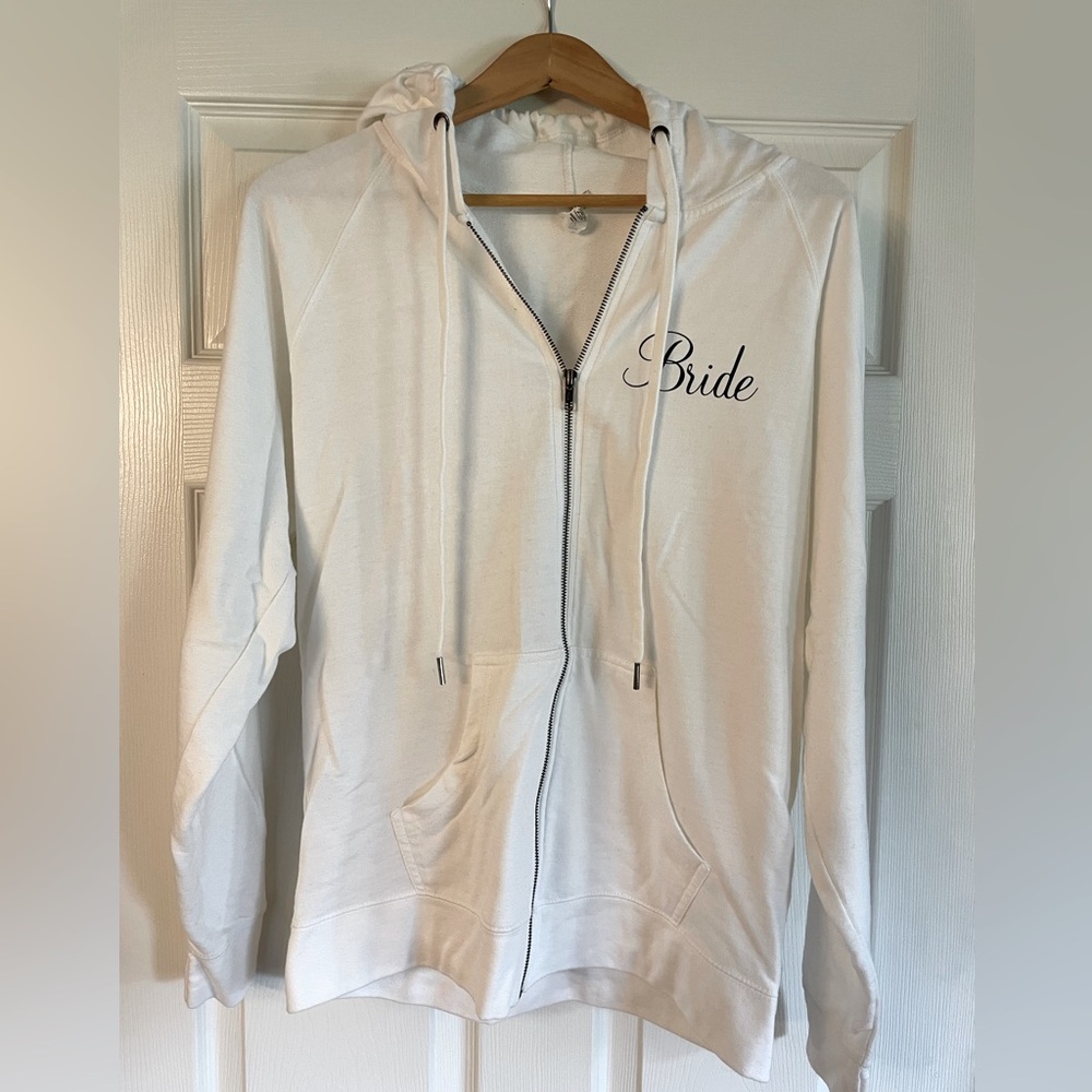 White zip up hoodie with “bride” on upper left chest.